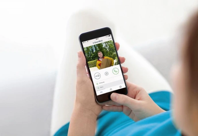 Persoon die een smartphone vasthoudt met de DoorBird‑app.